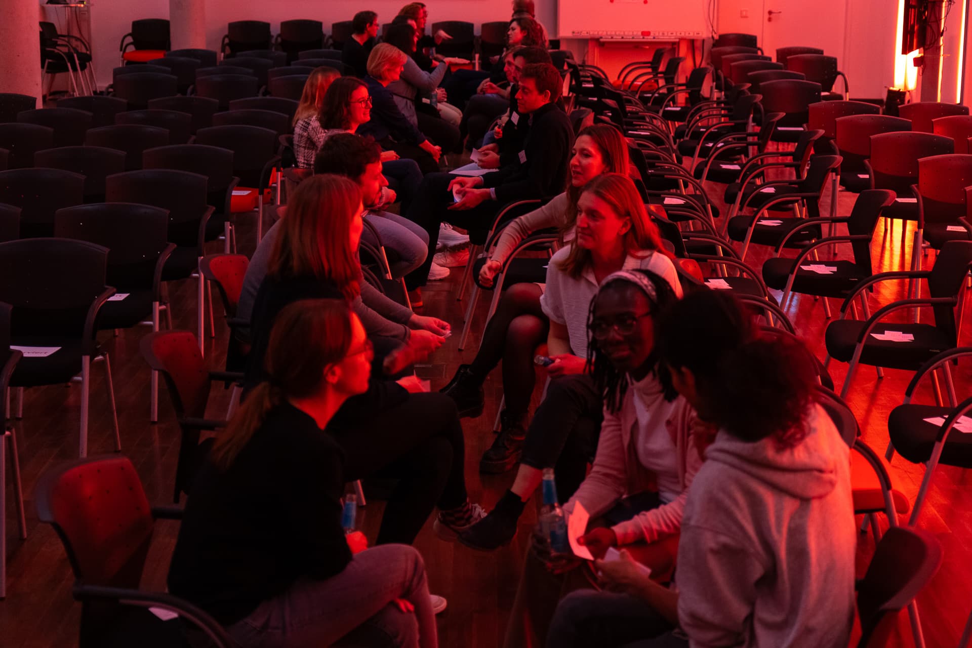 "Speeddating" von Alumni in einem rötlich-orange beleuchteten Raum