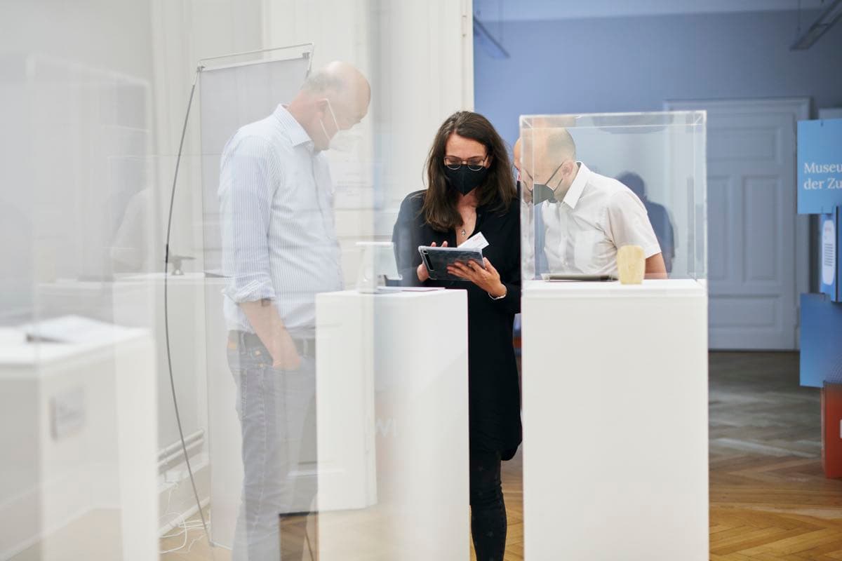 Three people operating a tablet as part of an exhibition