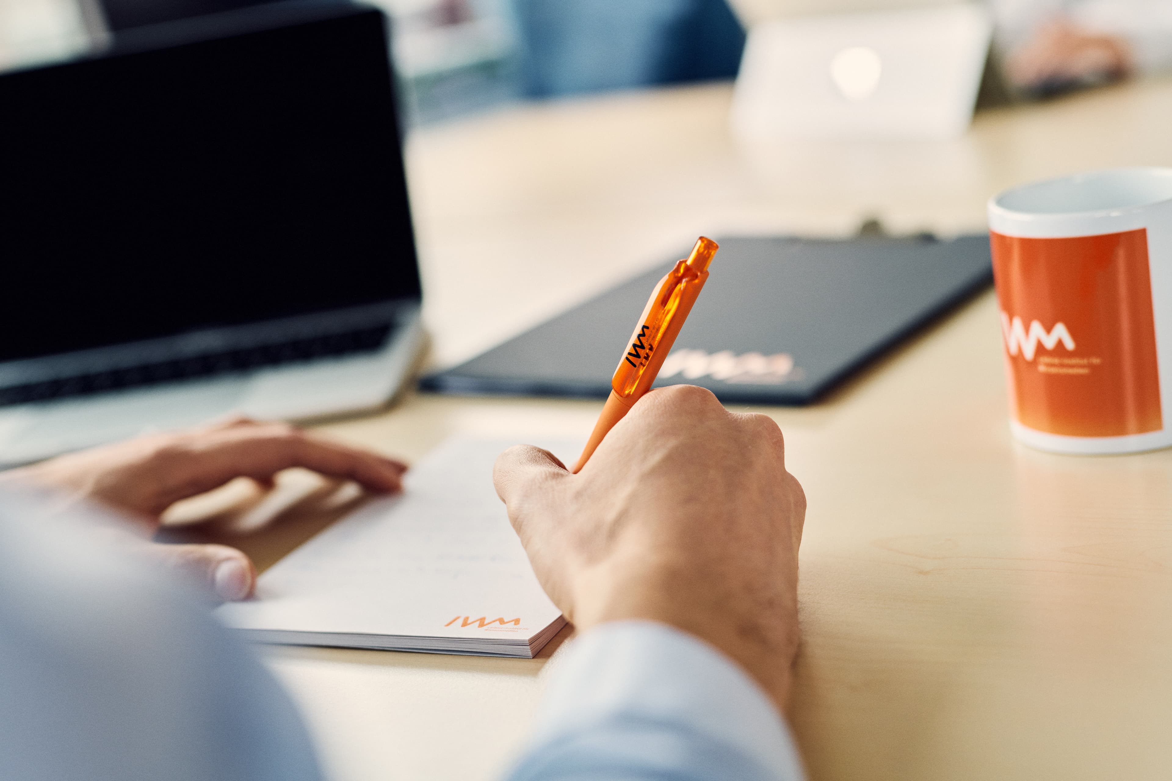 A person writing notes on an IWM notepad