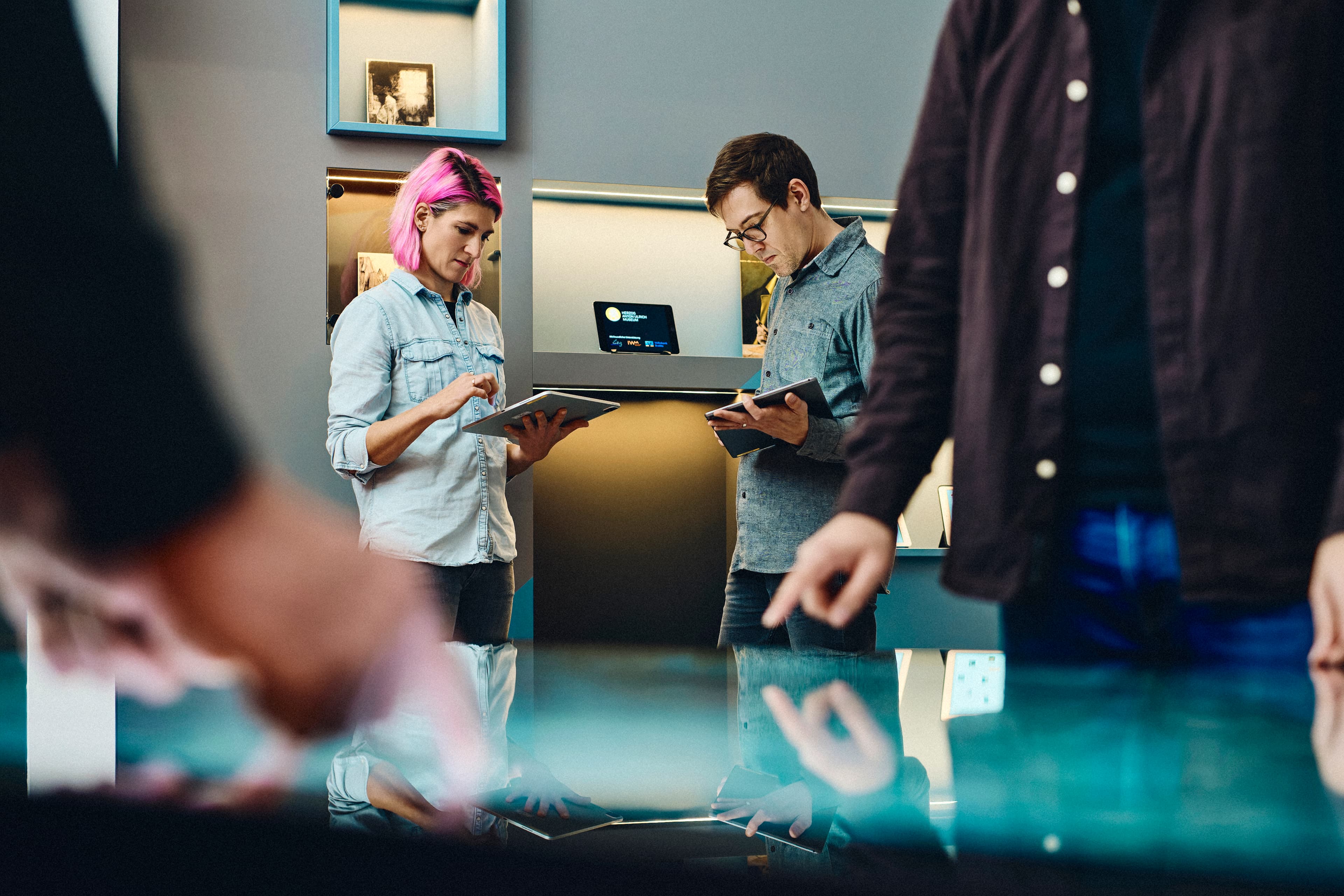 Two people operating a multi-touch table and two people with tablets in the background